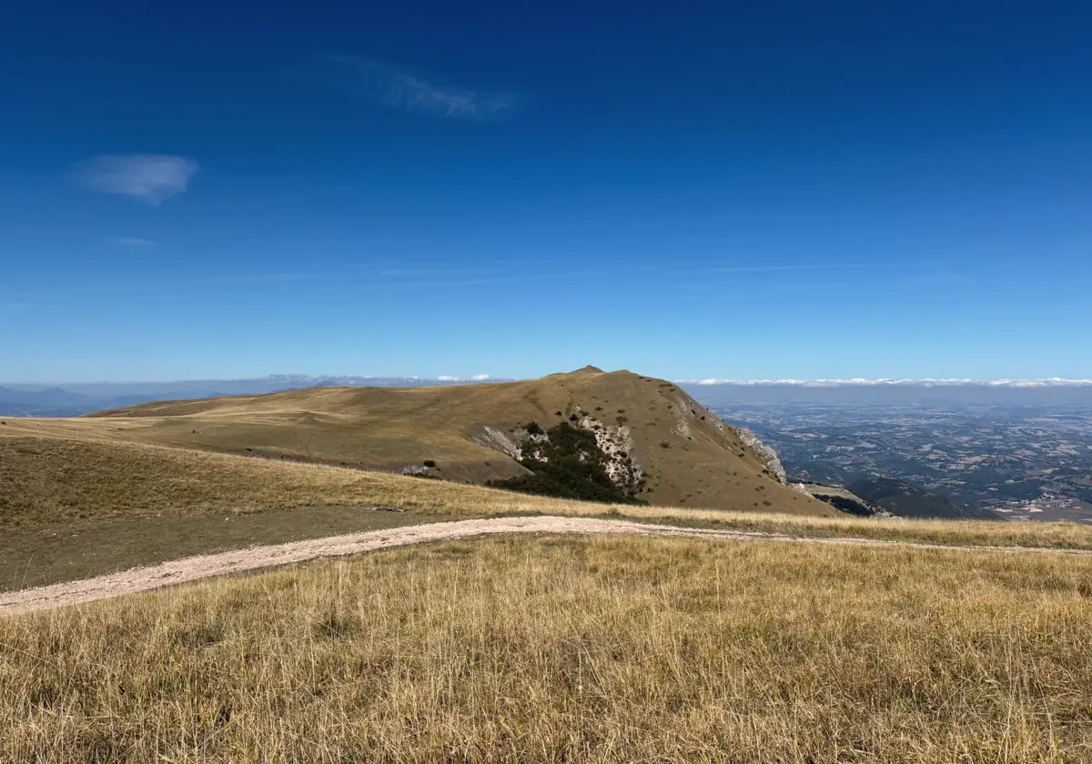 Un sentiero che corre sul crinale di un altopiano, con la valle sullo sfondo